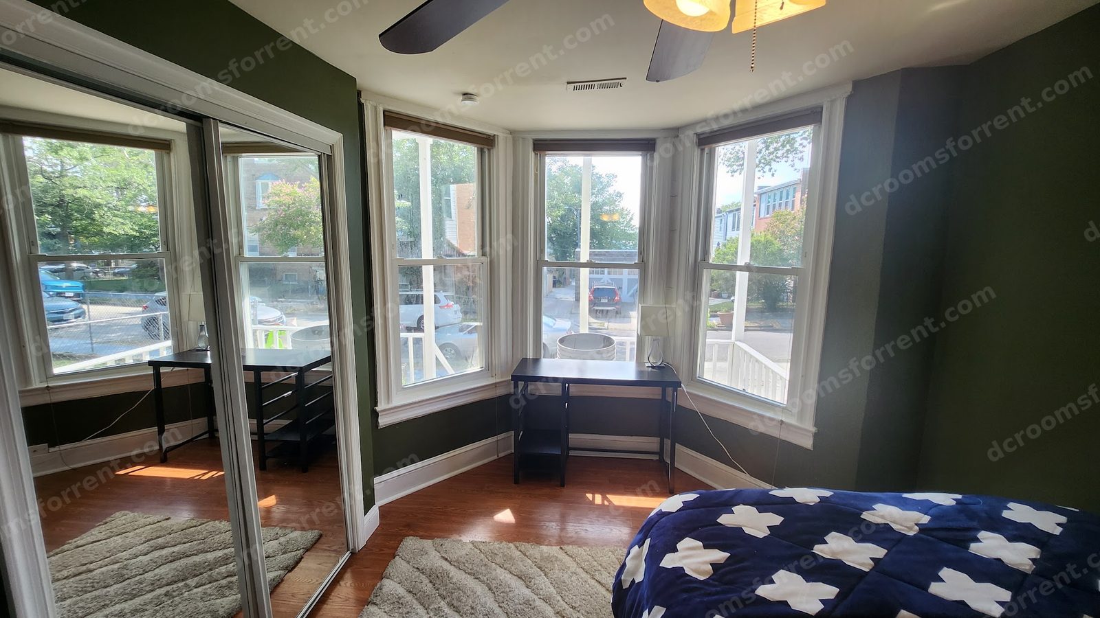 Delta Room: bright bay window overlooking the front yard, furnished with bed, desk, rug, and mirrored closet