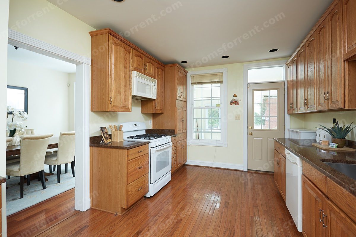Shared kitchen: gas stove, microwave, and oak cabinets, with dining room visible through doorway.
