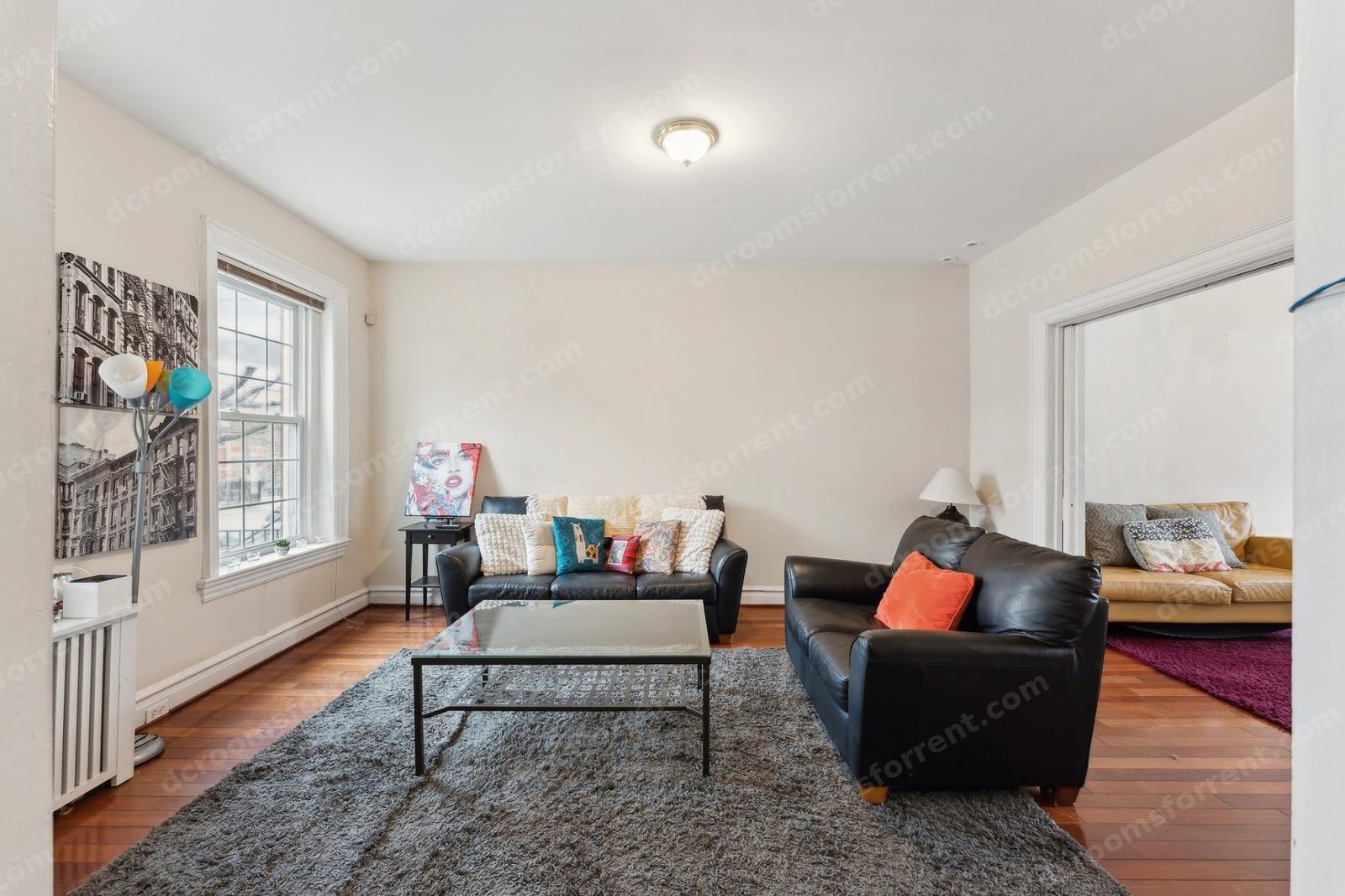 Shared living room with leather sofas, glass coffee table, and dining nook beyond.