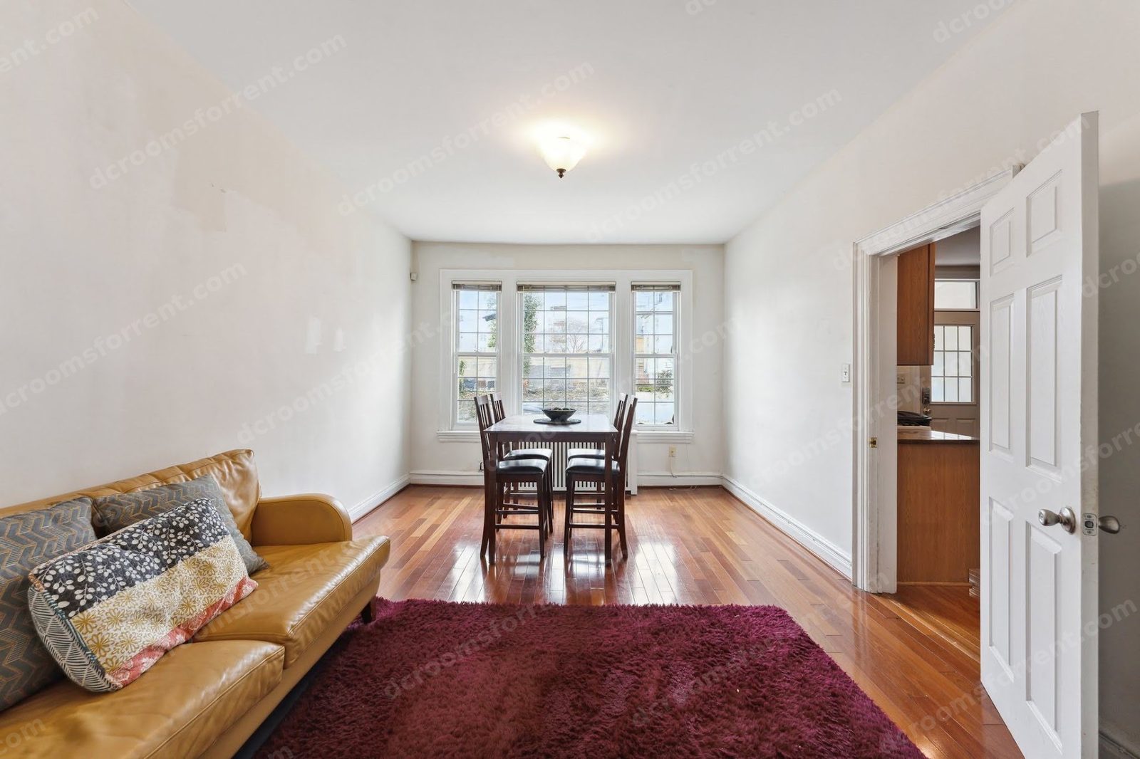 Dining nook with table, chairs, and tan sofa by the windows.