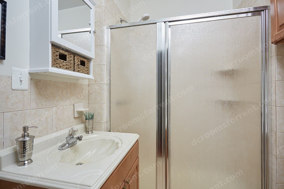 Shared bathroom with sink vanity and glass-door shower.
