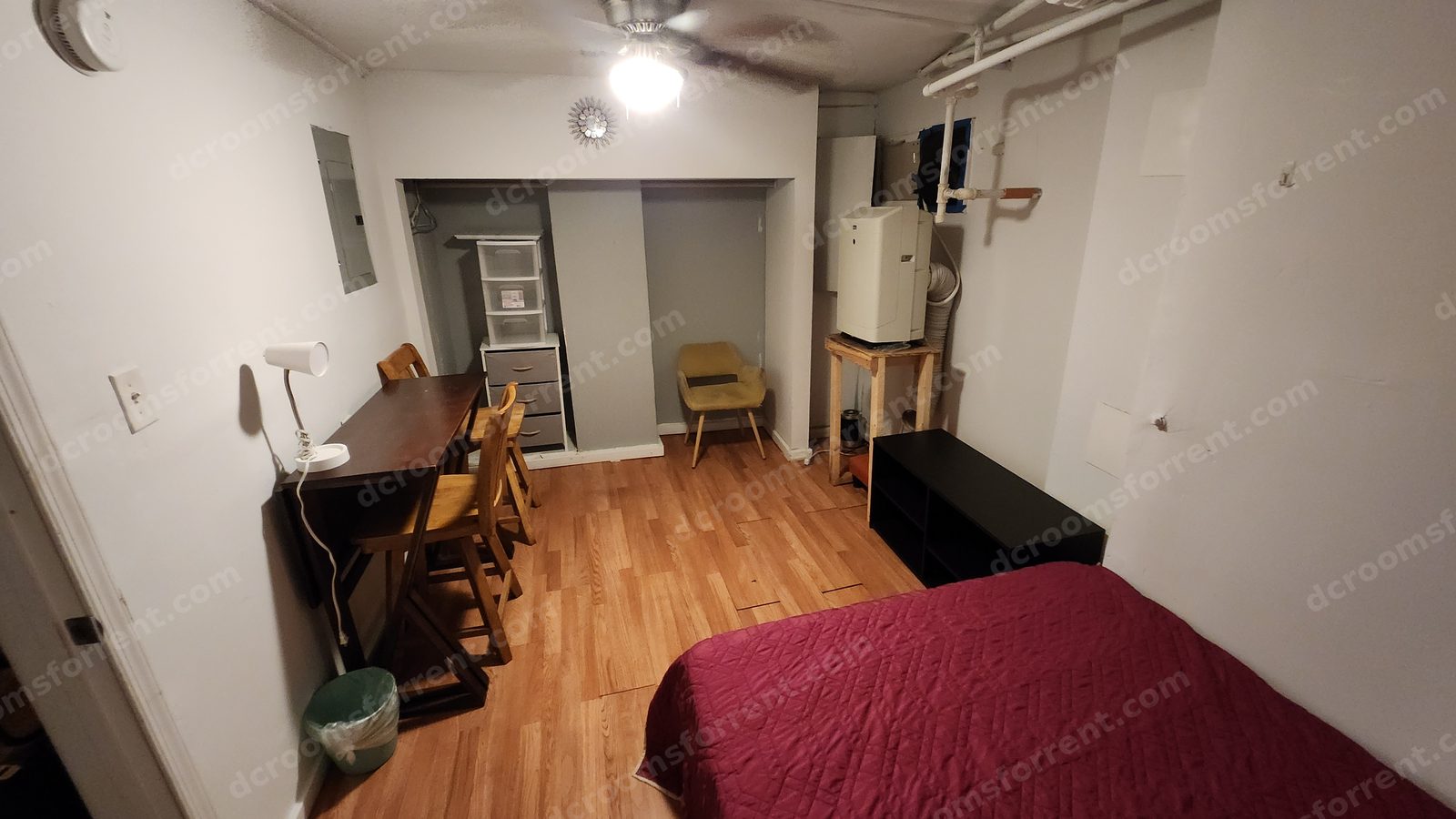 Lincoln Room viewed from the doorway: wood desk with chairs, closet alcove with storage drawers, armchair, and bed.