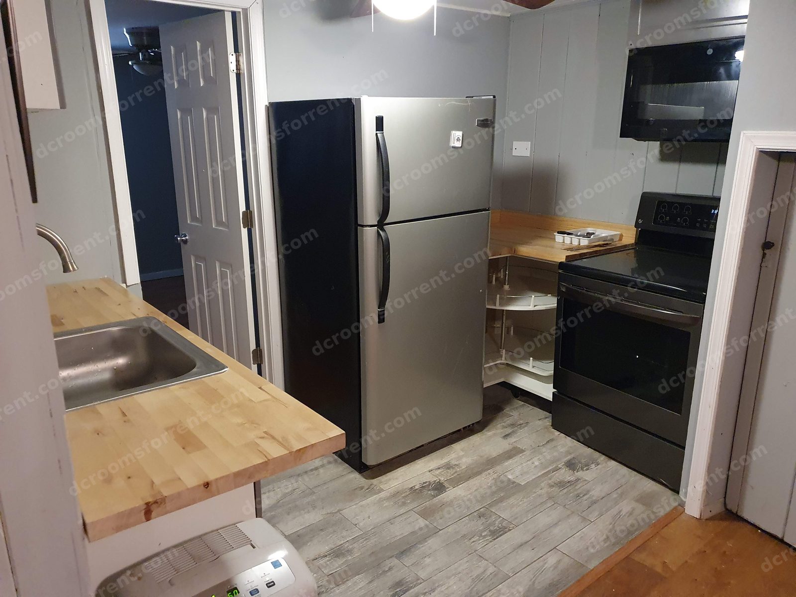 Shared kitchen with stainless sink, dishwasher, refrigerator, electric stove, and microwave; Lincoln Room through the doorway.
