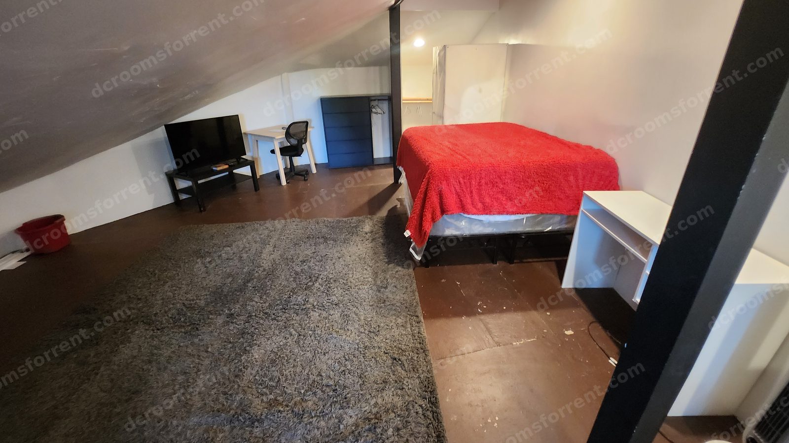 The huge Washington Room attic suite: bed, large rug, TV, desk, and dresser.