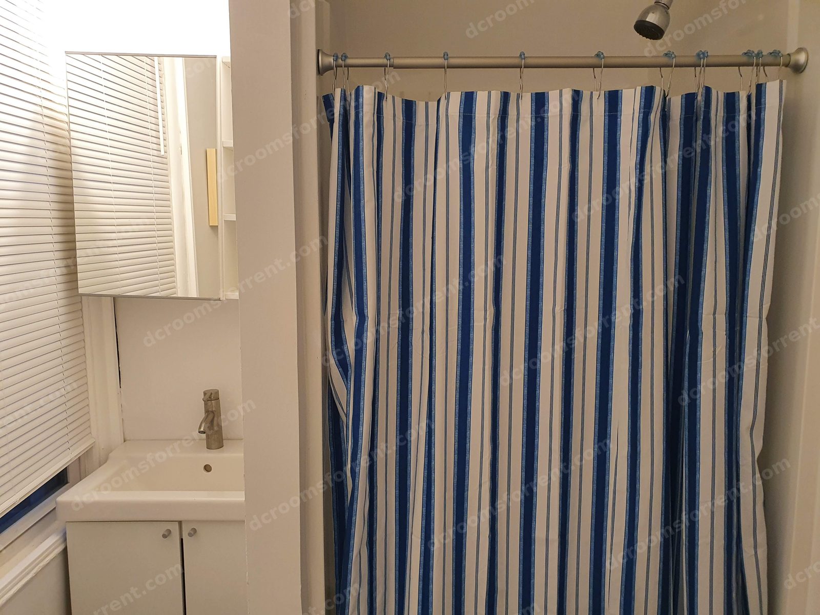 Shared bathroom: sink vanity and shower with striped curtain.